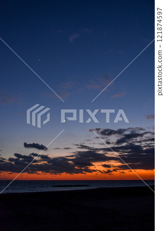 Beautiful crimson sunset and crescent moon over the sea 121874597