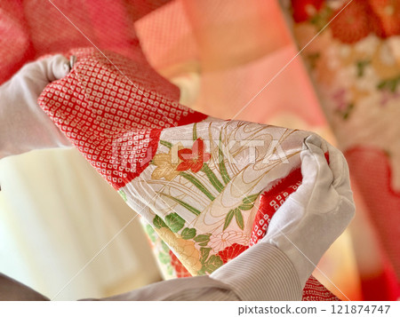 The hands of a person wearing white gloves looking at the pattern of a tie-dyed kimono The hands of a person wearing white gloves looking at the pattern of a tie-dyed kimono 121874747