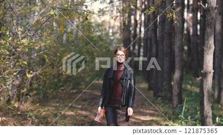 Smiling city woman relaxing in the forest. Thoughtful woman in glasses and office clothes walking in the autumn park, breathing fresh air, enjoying nature. Smiling city woman relaxing in the forest. Thoughtful woman in glasses and office clothes walking in the autumn park, breathing fresh air, enjoying nature. 121875365