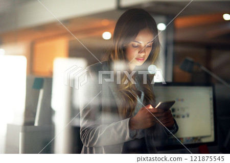 Business woman reading message on phone, checking notifications and browsing online for a cab after working late in dark office. Corporate professional, employee and worker scrolling on social media 121875545