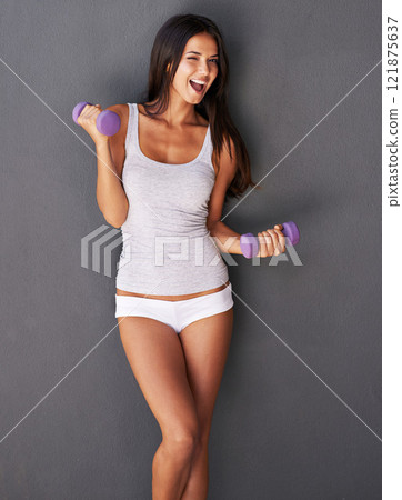 Fitness, exercise and health while being healthy, slim and fit during a dumbbell workout. Happy, cheerful and energetic woman feeling good while lifting weights and exercising to stay in shape 121875637