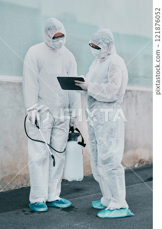 Healthcare workers cleaning outside a building using a list to follow instructions on biohazard safety during covid. Medical researchers wearing hazmat suits sanitizing outdoor to prevent infections 121876052