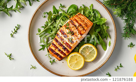 healthy meal featuring grilled salmon on bed of fresh greens, garnished with lemon slices and herbs, perfect for nutritious dining experience 121876188