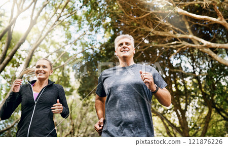 Fit, active and healthy mature couple jogging, running and enjoying their fitness lifestyle outside in nature during summer. Happy, smiling and free senior man and sporty woman exercise together 121876226