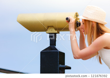 Woman tourist with sun hat looking through telescope 121876392