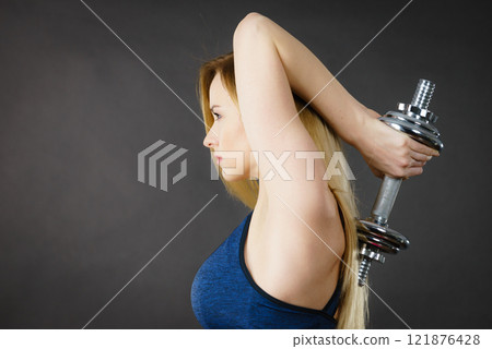 Fit woman lifting dumbbells weights Fit woman lifting dumbbells weights 121876428