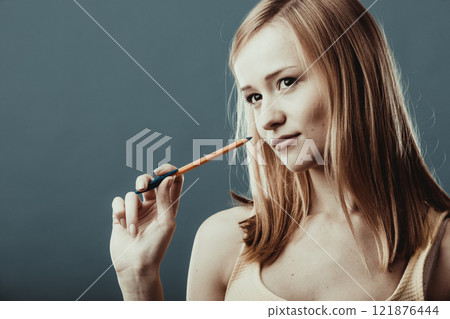 blonde girl thinking holds pen on gray background 121876444