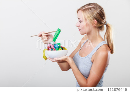 Diet. Girl with colorful measuring tapes in bowl 121876446