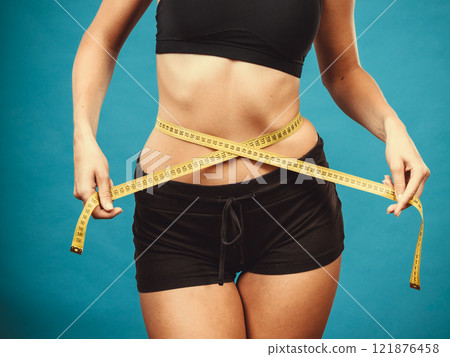 Fitness girl measuring her waistline 121876458