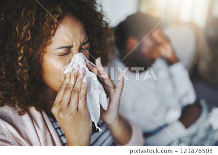 Ill or sick woman with allergy, sinus infection sneezing in tissue or blowing nose during flu season at home. Sick girl caught a bad cold showing symptoms of covid, or suffering from a virus disease 121876503