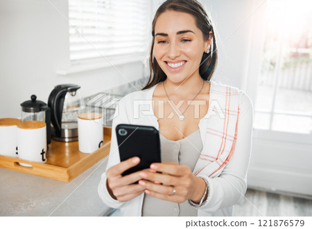 Woman browsing, texting and reading on a phone in her kitchen at home. Smiling woman on social media online app, networking and messaging contacts while smiling at a funny post, meme or videos Woman browsing, texting and reading on a phone in her kitchen at home. Smiling woman on social media online app, networking and messaging contacts while smiling at a funny post, meme or videos 121876579