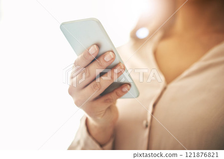 Phone in hand, communication and networking with a woman reading, typing or sending a text message. Closeup of a female browsing social media, surfing the internet and checking news online with flare Phone in hand, communication and networking with a woman reading, typing or sending a text message. Closeup of a female browsing social media, surfing the internet and checking news online with flare 121876821