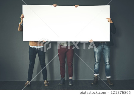Group of businesspeople holding up a copyspace sign voicing their opinion at work with a grey background. People with blank poster advertising, marketing and express or convey important messages 121876865