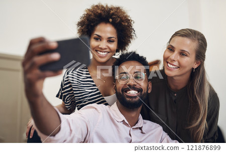 Group of office friends taking a happy selfie using a phone in business place. Cheerful, excited and joyful colleagues, work team and coworkers taking fun photos together. 121876899
