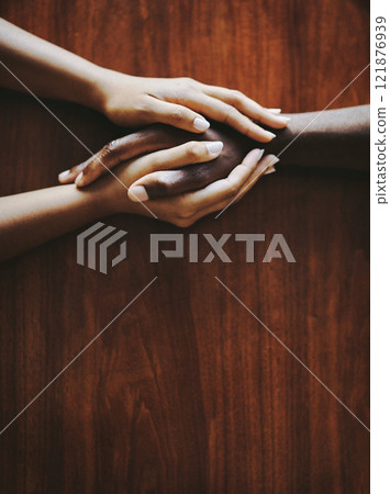 Support, love and a couple holding hands at a table from above with copyspace. Interracial friends praying, consoling and showing care at therapy or after bad news. Unity and affection after grief. Support, love and a couple holding hands at a table from above with copyspace. Interracial friends praying, consoling and showing care at therapy or after bad news. Unity and affection after grief. 121876939