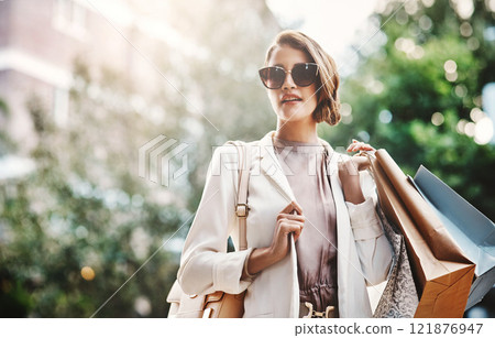 Trendy, fashionable and elegant woman enjoying shopping in the city. Young female coming from a sale downtown, holding shopping bags while looking satisfied. Lady spending the day on retail therapy 121876947