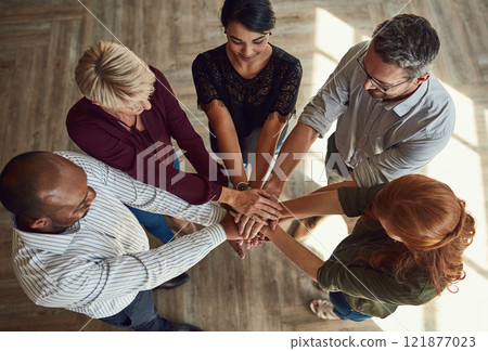 A group of business professionals putting their hands together in unity, supporting each other and standing as a team top view. Diverse male and female design company employees uniting for a project 121877023
