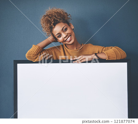 Board, announcement and empty copyspace by a smiling African American young lady. Beautiful, cheerful and happy woman standing in the background behind poster. Confident black woman presenting sign. Board, announcement and empty copyspace by a smiling African American young lady. Beautiful, cheerful and happy woman standing in the background behind poster. Confident black woman presenting sign. 121877074