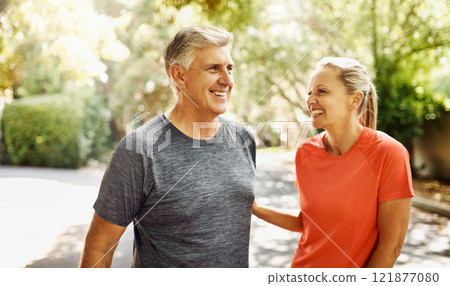 Happy mature couple keeping active, fit and healthy while jogging, running or going for walk outdoors in nature environment. Laughing senior man and woman enjoying a break from workout or exercising 121877080