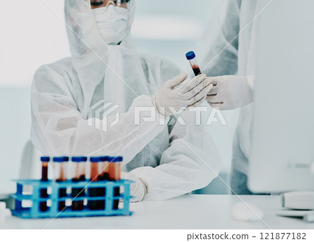 Scientists testing covid blood sample with protective ppe to prevent spread of virus in hospital. Pair of doctors or medical workers wearing hazmat suits doing experimental research in lab. 121877182