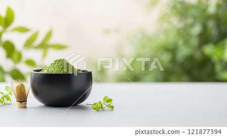 Green matcha powder in black bowl with whisk on table 121877394