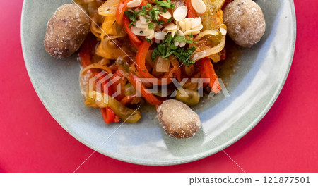 Delicious dish with a cod fillet fish, boiled potatoes and peppers on the red background. Delicious dish with a cod fillet fish, boiled potatoes and peppers on the red background. 121877501