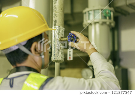 A male worker closes a valve. Photo courtesy of Denpa Gakuen, Tokyo Electronics College. 121877547