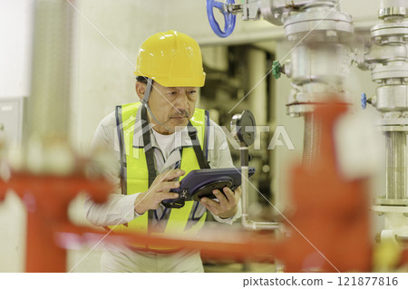 A male worker inspecting a building with a tablet. Photo courtesy of Denpa Gakuen, Tokyo Electronics College. 121877816