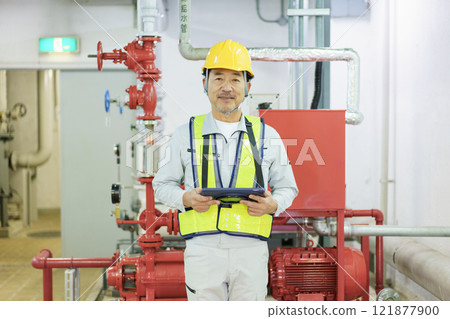 一名男性工人拿著平板電腦站立。 121877900