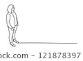 Woman stands in front of a wall, looking at something behind her 121878397