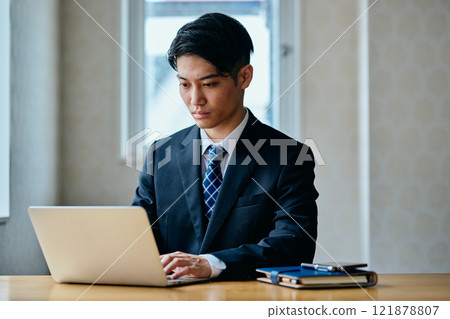 A young man in his twenties operating a personal computer A young man in his twenties operating a personal computer 121878807