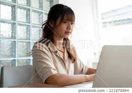 Young woman engages in online study at workspace. 121878864