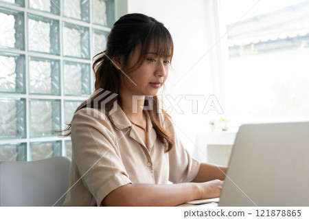 Young woman engages in online study at workspace. 121878865