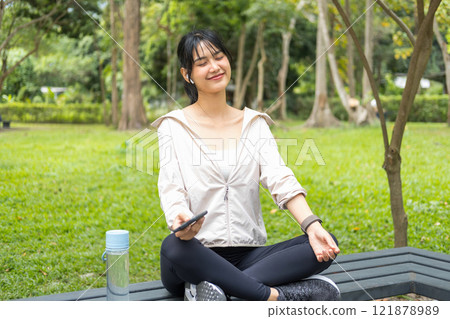 Young woman sitting and listening to music at the park. Young woman sitting and listening to music at the park. 121878989