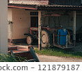 Rural landscape featuring a parked tractor near a rustic shed at midday 121879187