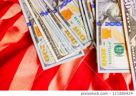 Collection of American hundred dollar bills laid on bright fabric textures showcasing currency details 121880424