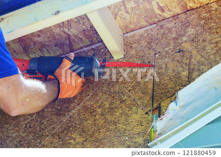 Contractor carefully cuts plywood above while renovating home, showcasing skill on craftsmanship. 121880459