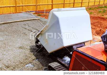Wheelbarrow truck concrete mixer pours fresh cement onto construction site, preparing slab for new structure 121880469