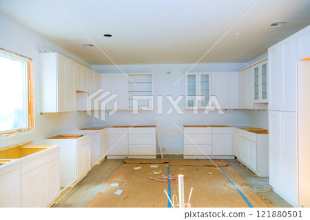 Brightly lit kitchen undergoing renovation with white cabinets unfinished countertops awaiting completion. Brightly lit kitchen undergoing renovation with white cabinets unfinished countertops awaiting completion. 121880501