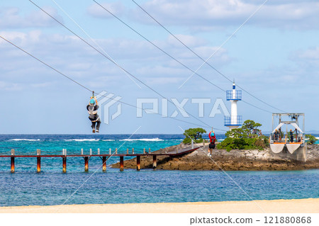 White sand beach, blue sea and sky. Zip line over the sea at Sheraton Okinawa Sunmarina Resort. 121880868