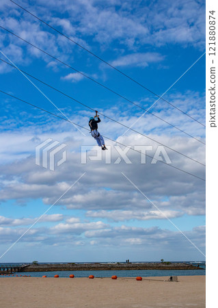 White sand beach, blue sea and sky. Zip line over the sea at Sheraton Okinawa Sunmarina Resort. 121880874