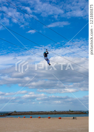 White sand beach, blue sea and sky. Zip line over the sea at Sheraton Okinawa Sunmarina Resort. 121880875