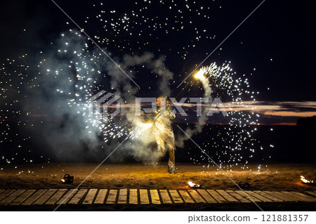 A girl lights a sparkler on the beach at dusk. A girl lights a sparkler on the beach at dusk. 121881357