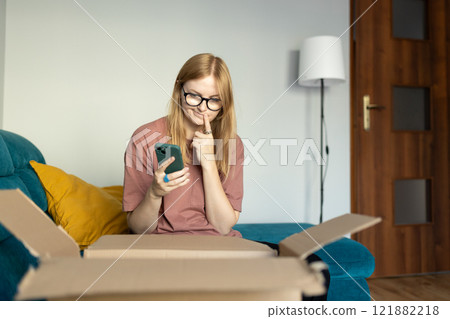 Annoyed confused blonde woman frustrated by wrong order shopping online using smartphone. Upset female buyer unbox parcel buying on web confused with bad delivery service. Shipping concept Annoyed confused blonde woman frustrated by wrong order shopping online using smartphone. Upset female buyer unbox parcel buying on web confused with bad delivery service. Shipping concept 121882218