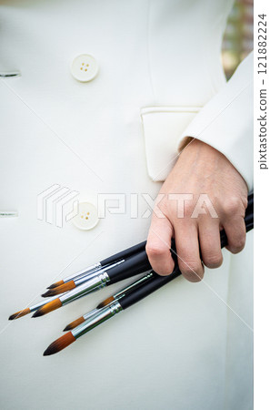 Brunette, female artist paints in nature. 121882224