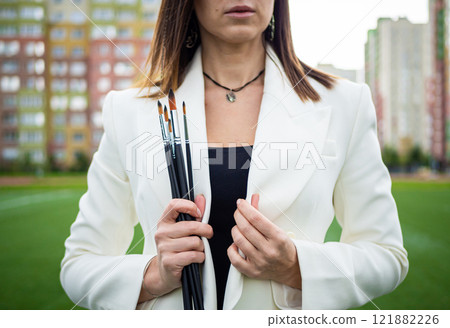 Brunette, female artist paints in nature. 121882226