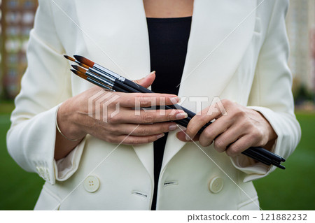 Brunette, female artist paints in nature. 121882232