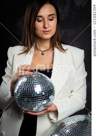 Portrait of a woman holding a silver disco ball. Taken in a photo studio. Portrait of a woman holding a silver disco ball. Taken in a photo studio. 121882304