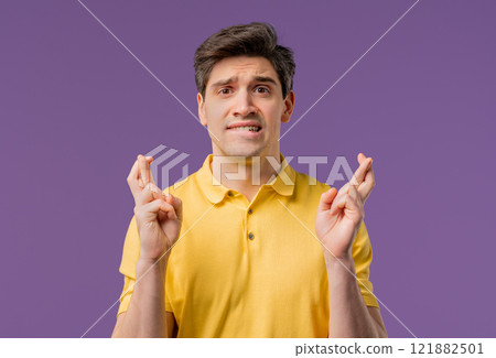 Adult 30s man praying with crossed fingers on violet background. Guy begs God help Adult 30s man praying with crossed fingers on violet background. Guy begs God help 121882501