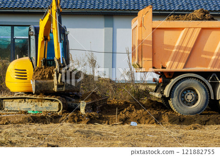 Excavator moves soil from ground into dump truck at construction site during construction Excavator moves soil from ground into dump truck at construction site during construction 121882755